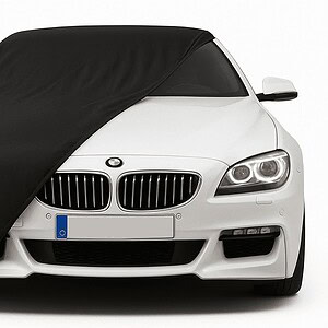 Czarny pokrowiec na białe BMW, chroniący przed kurzem i zarysowaniami.