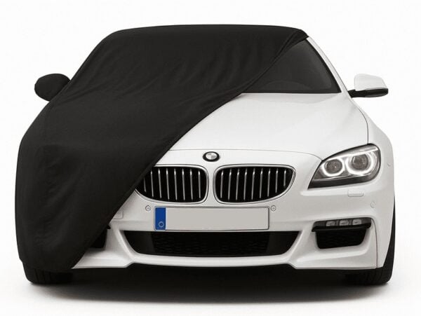 Czarny pokrowiec na białe BMW, chroniący przed kurzem i zarysowaniami.